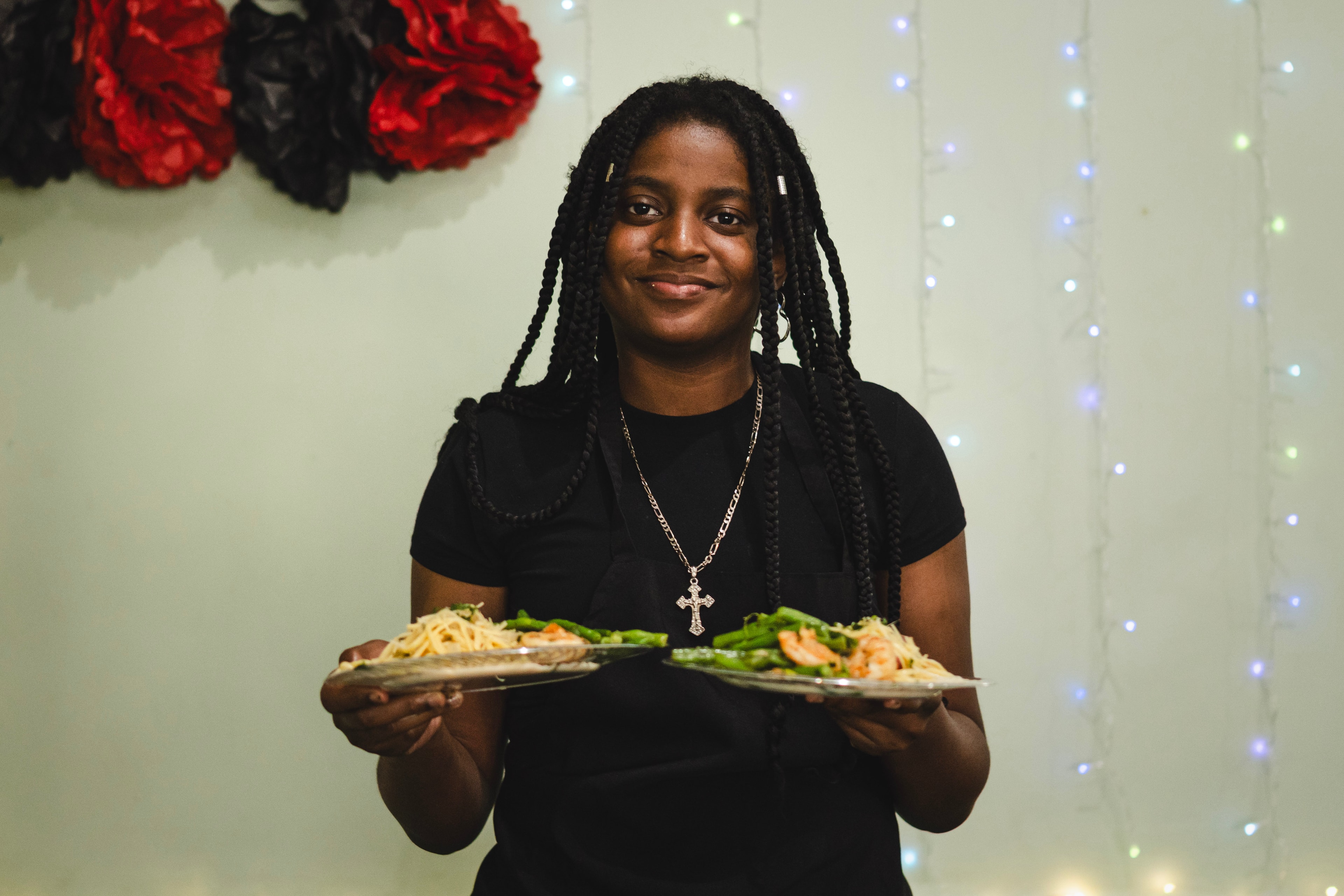 Student proudly holding two plates of shrimp pasta
