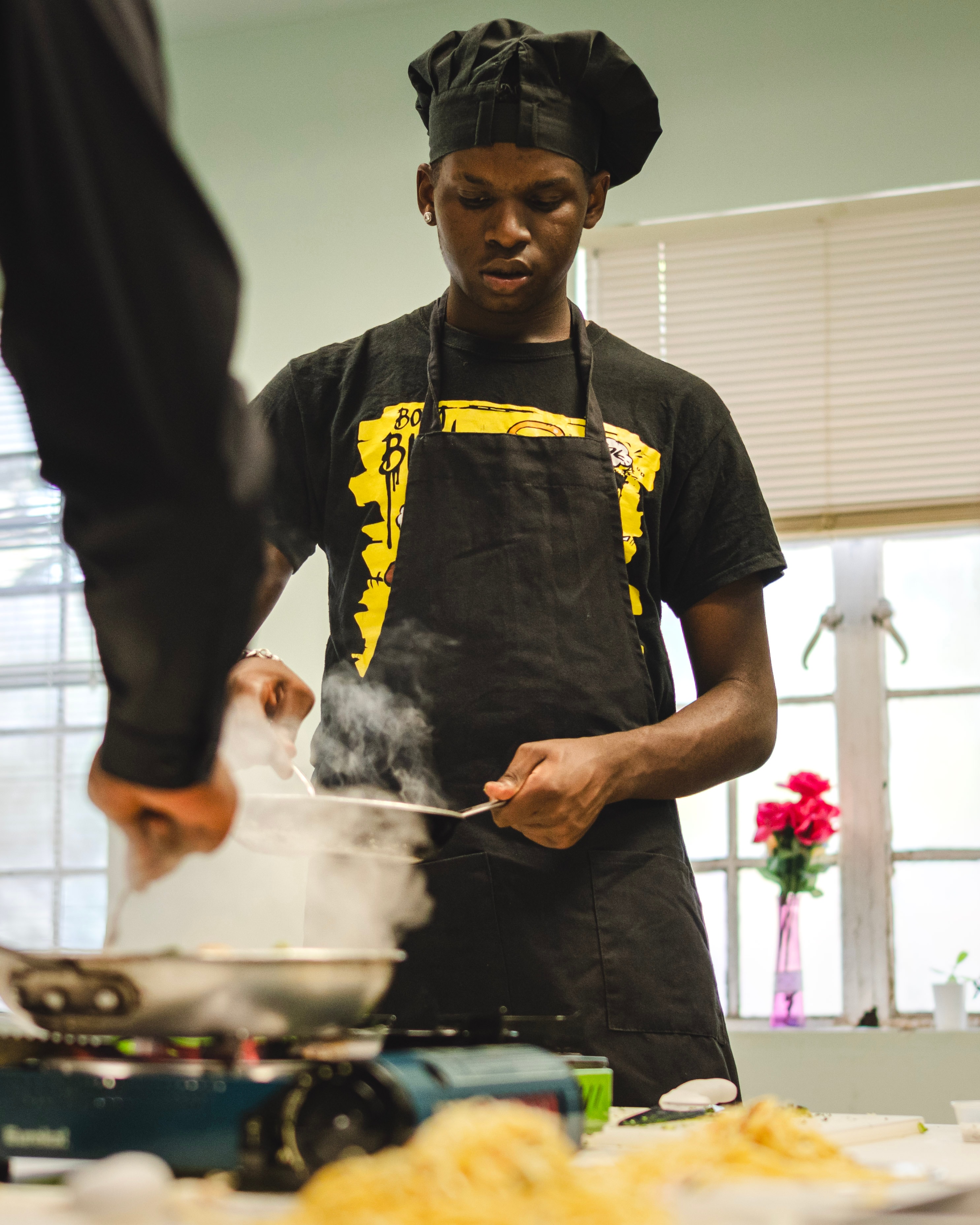 Young chef in a chef hat cooking at the stove