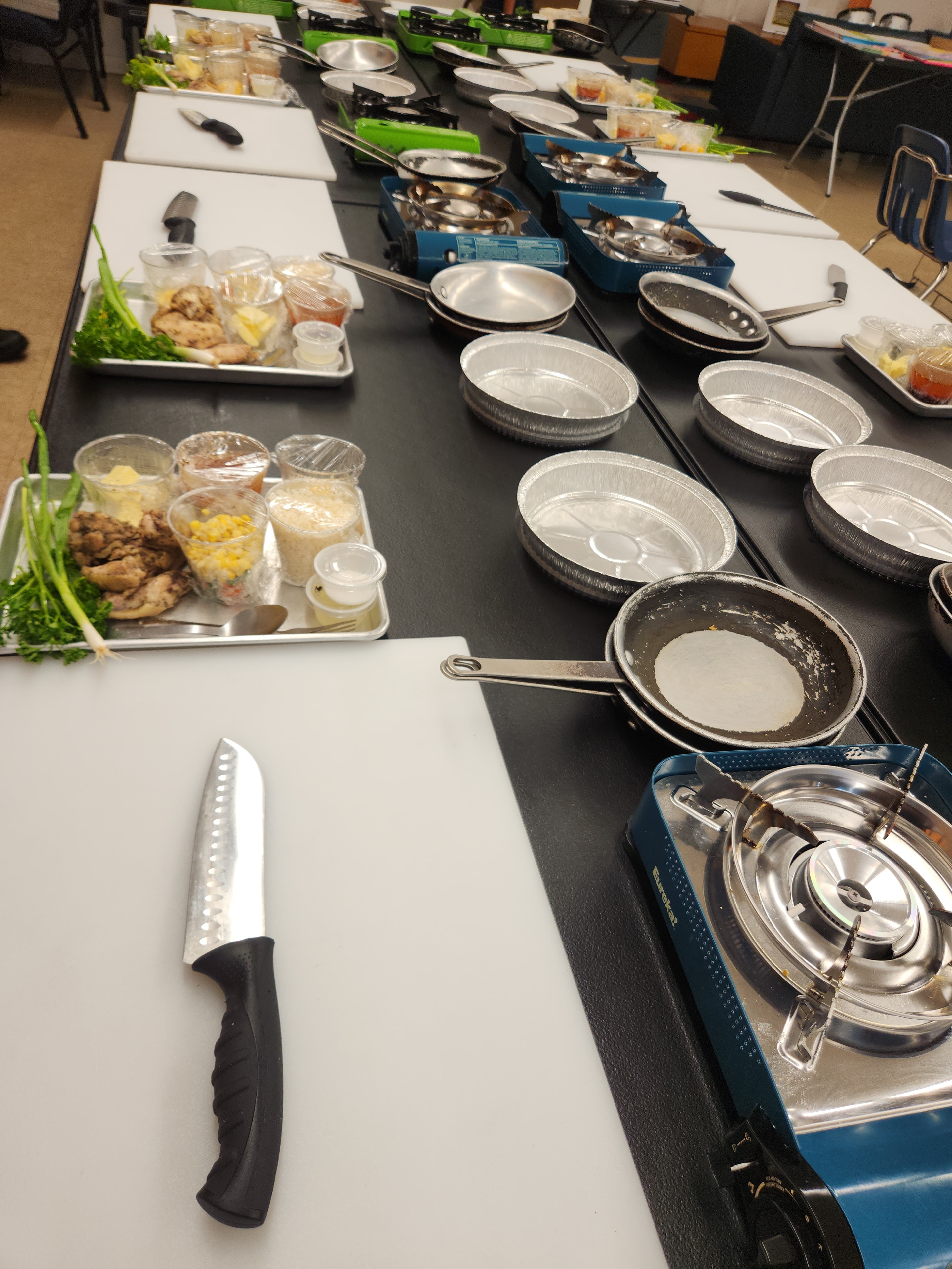 Kitchen station setup with pans, cutting boards, and portable burners