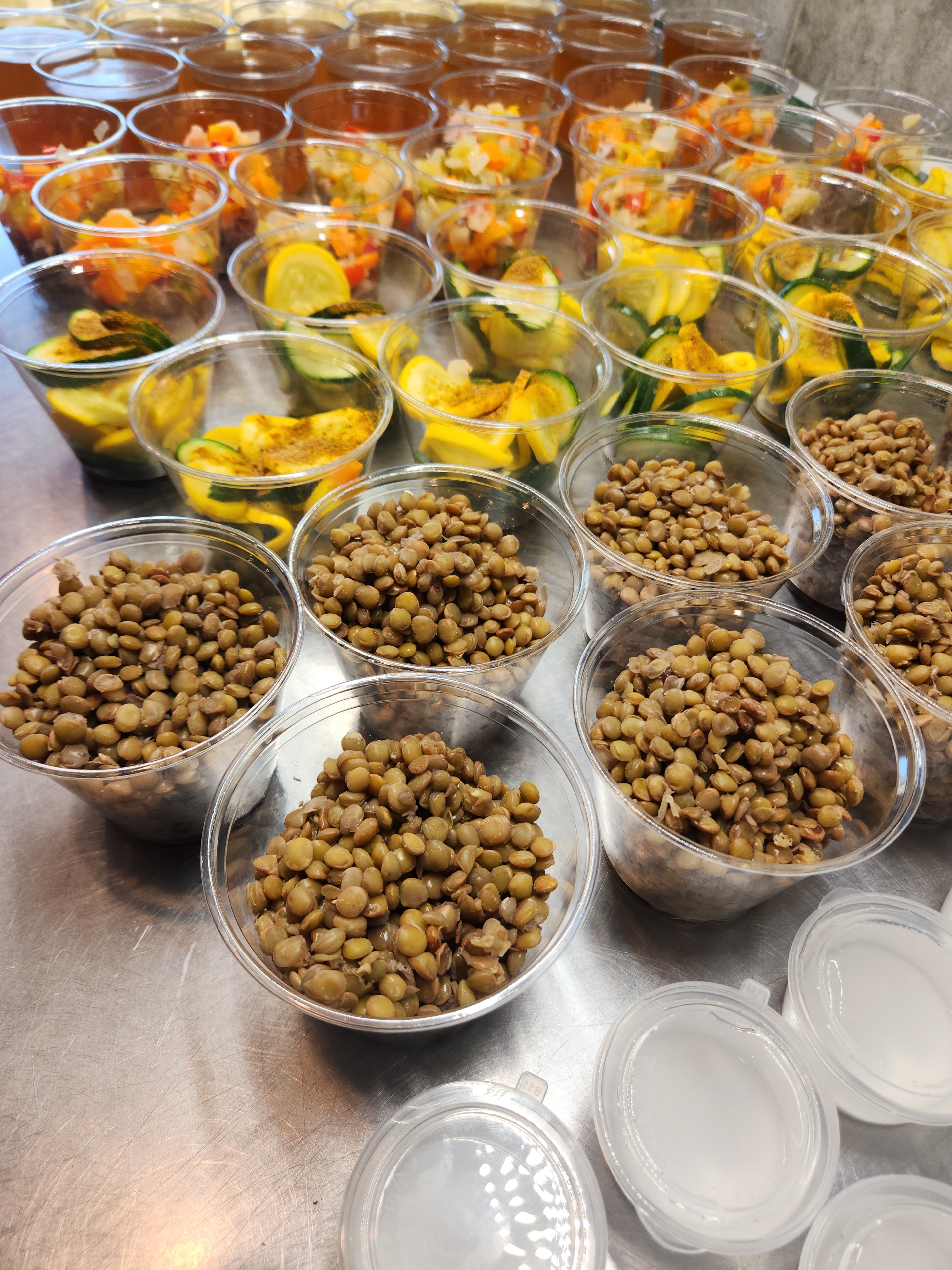 Prepped lentil and roasted vegetable cups on a steel table