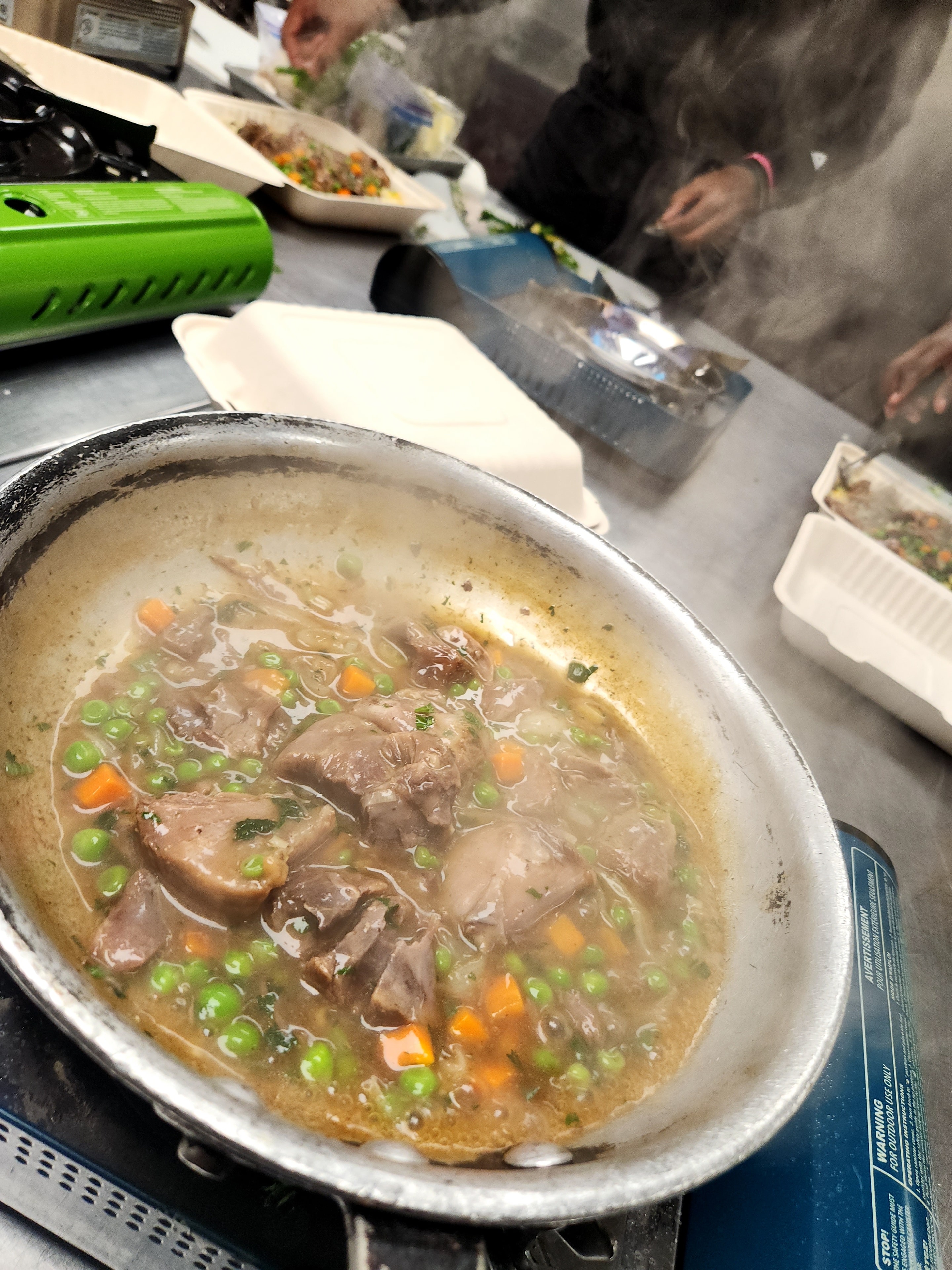 Braised meat with peas and carrots simmering in a pan
