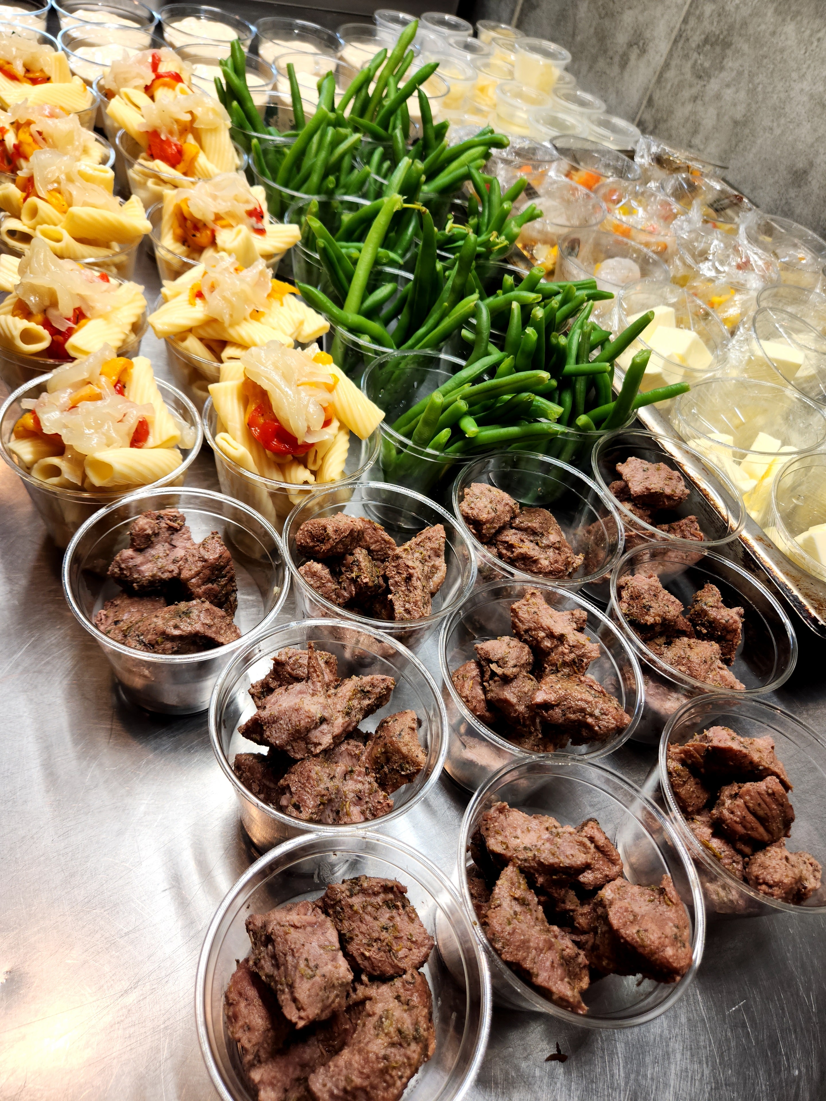 Prepped pasta salad, green beans, and seasoned meat cups