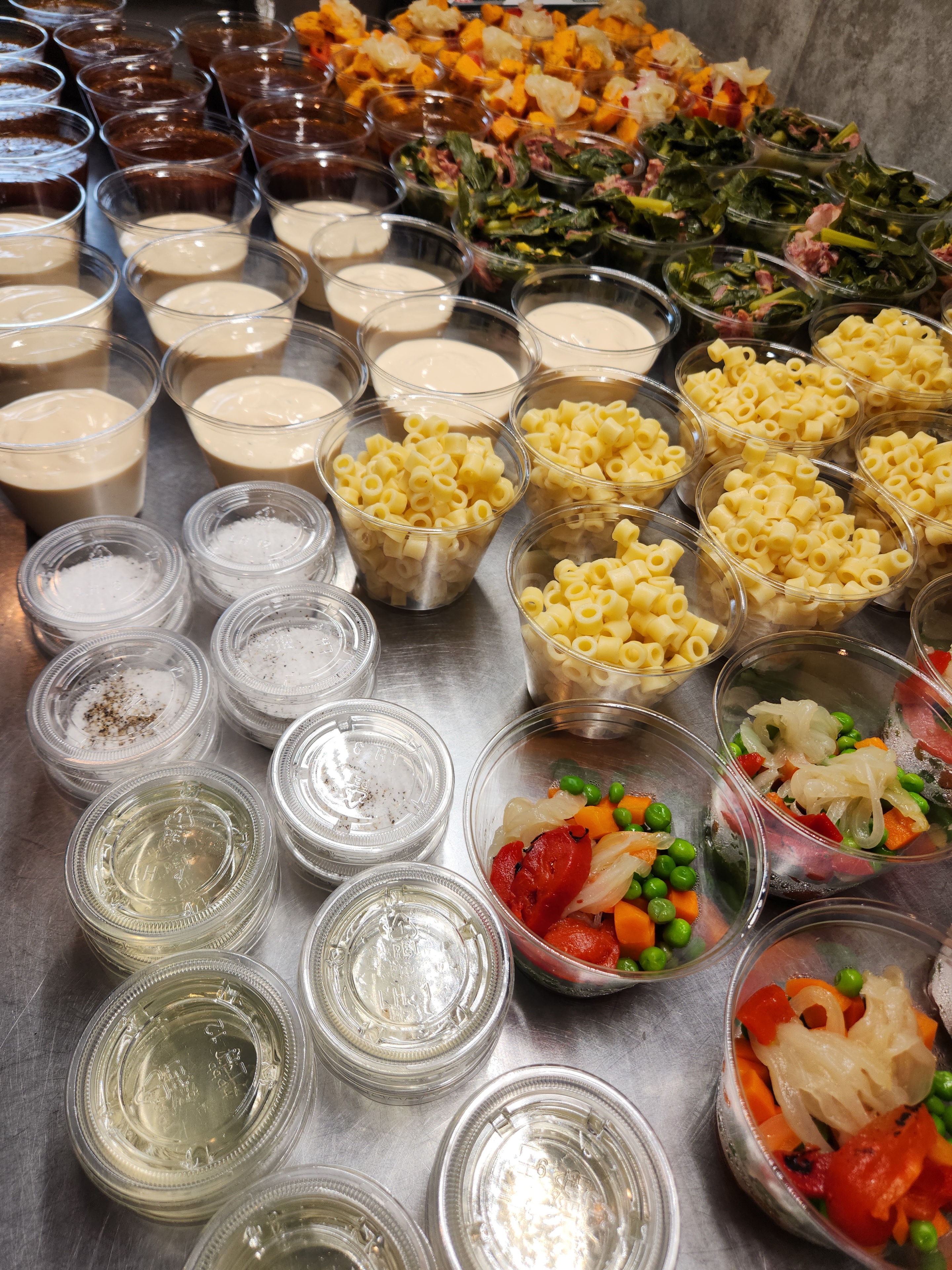 Overhead view of prepped pasta, vegetables, and sauce cups