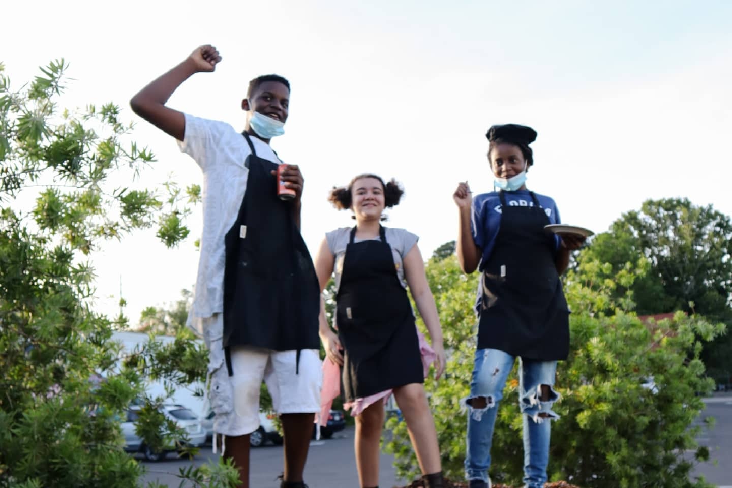 Three young chefs in aprons celebrating outside after class