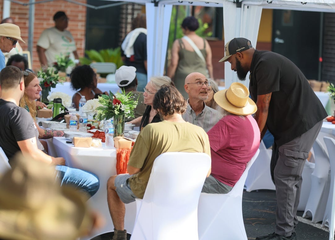 Guests enjoying a community meal together at outdoor tables