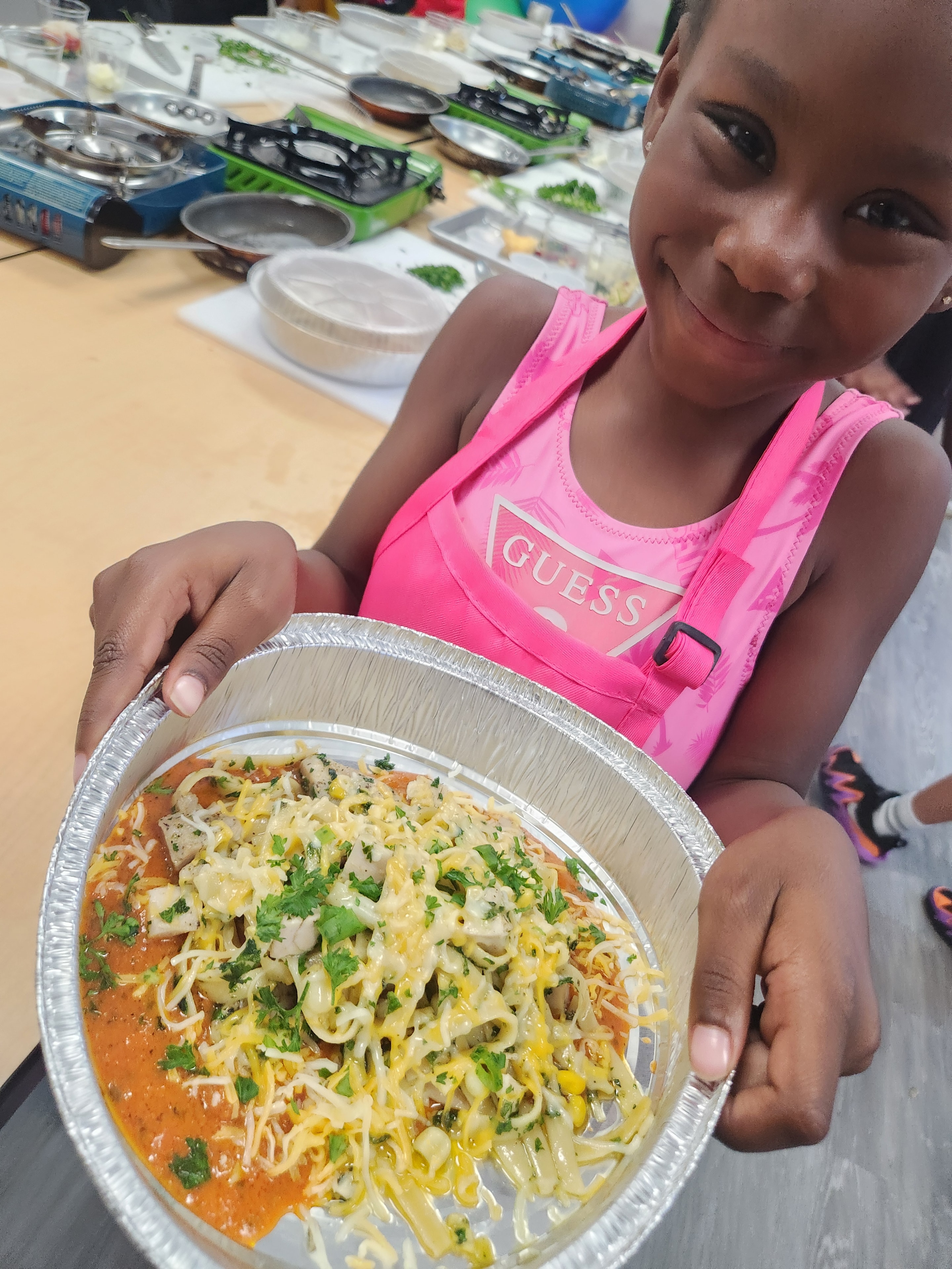 Young student showing off her pasta dish